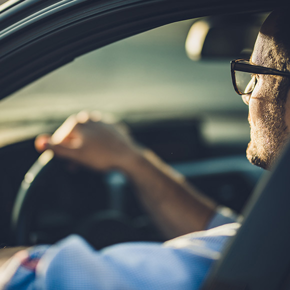 Man in glasses driving car to depict motor insurance by Find Insurance NI