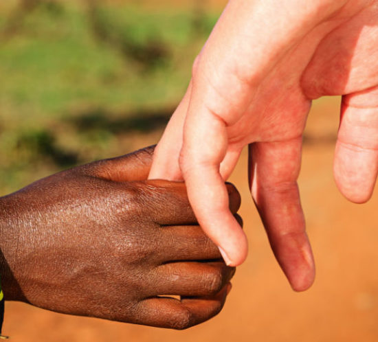 Volunteer holding hands with an african child for Find Insurance NI blog