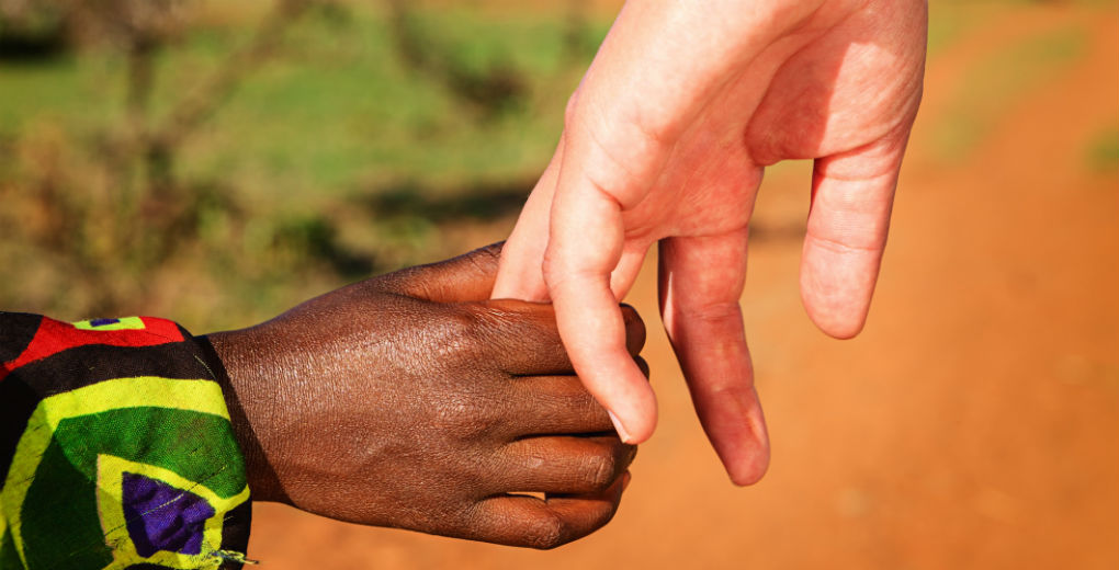 Volunteer holding hands with an african child for Find Insurance NI blog